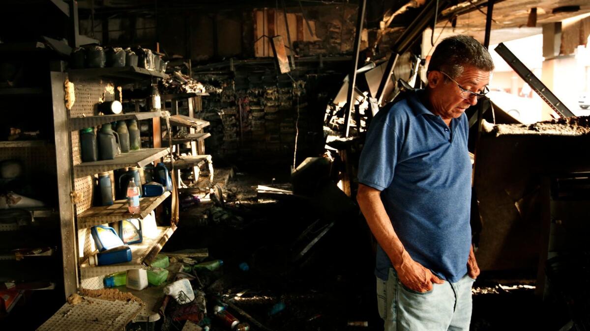 A cafe owner stands in the ruins of a shopping area in San Juan on Monday. A nearby drugstore had been targeted by looters.