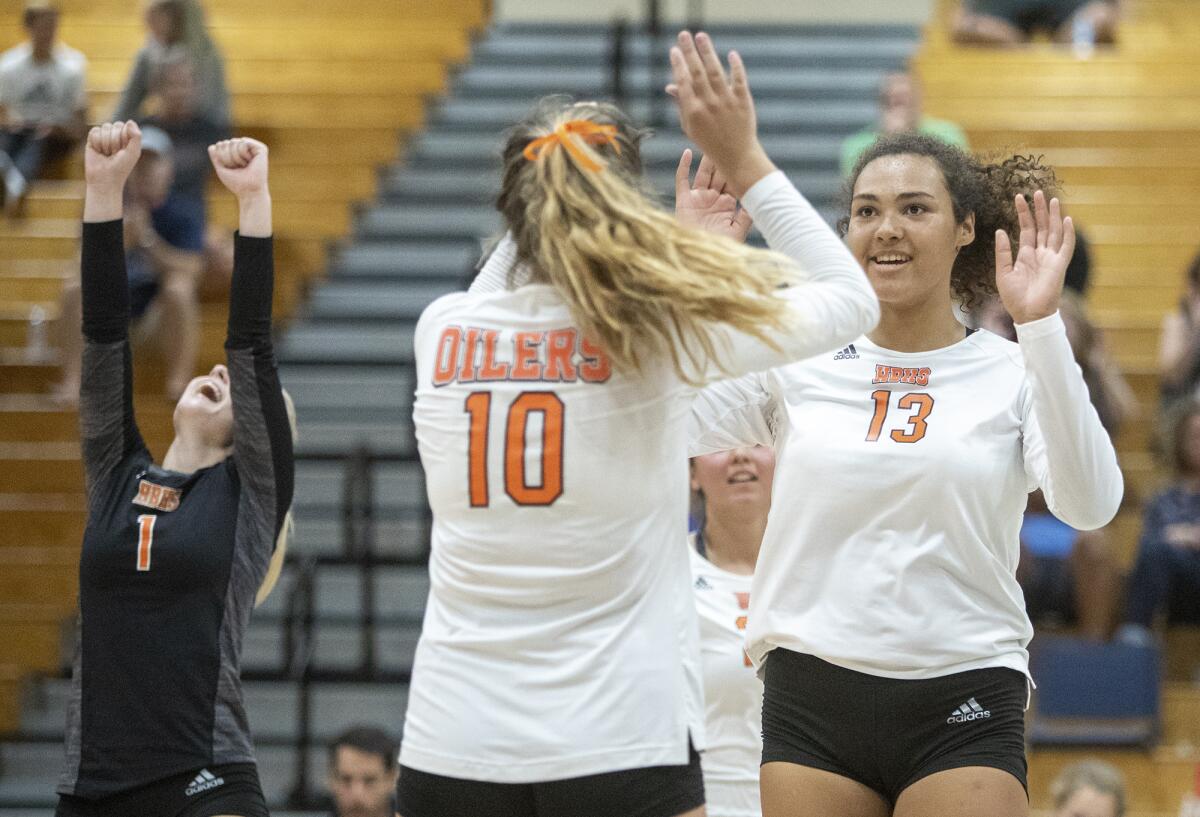 Huntington Beach's Olivia Carlton (13) high-fives Jaclyn Sanchez after scoring a point in a Surf League home match against Edison on Thursday.