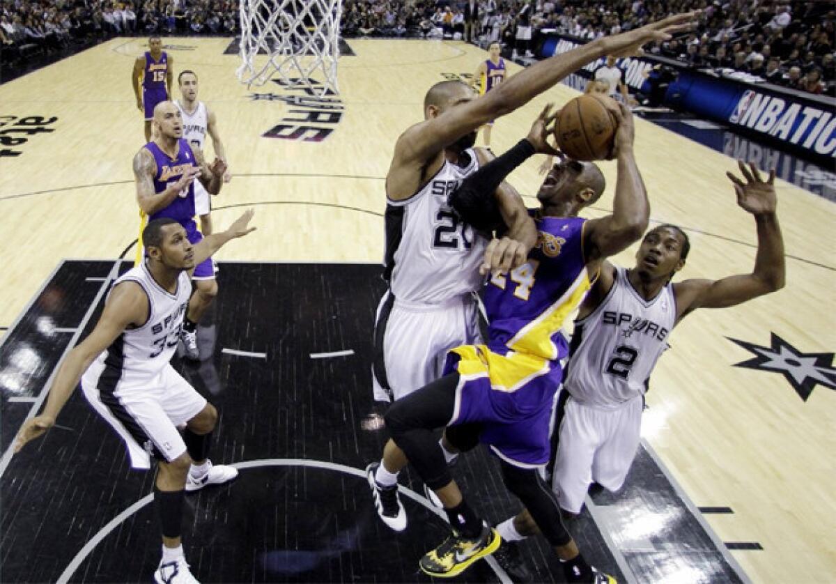 Spurs big man Tim Duncan blocks Lakers guard Kobe Bryant in front of the rim.