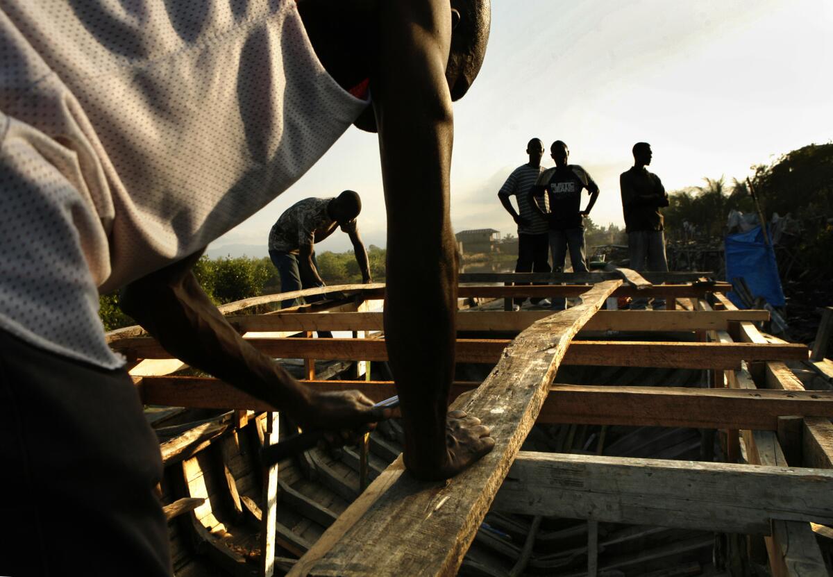 A Haitian man works in 2010 on building a boat he hopes to use to get to the United States.
