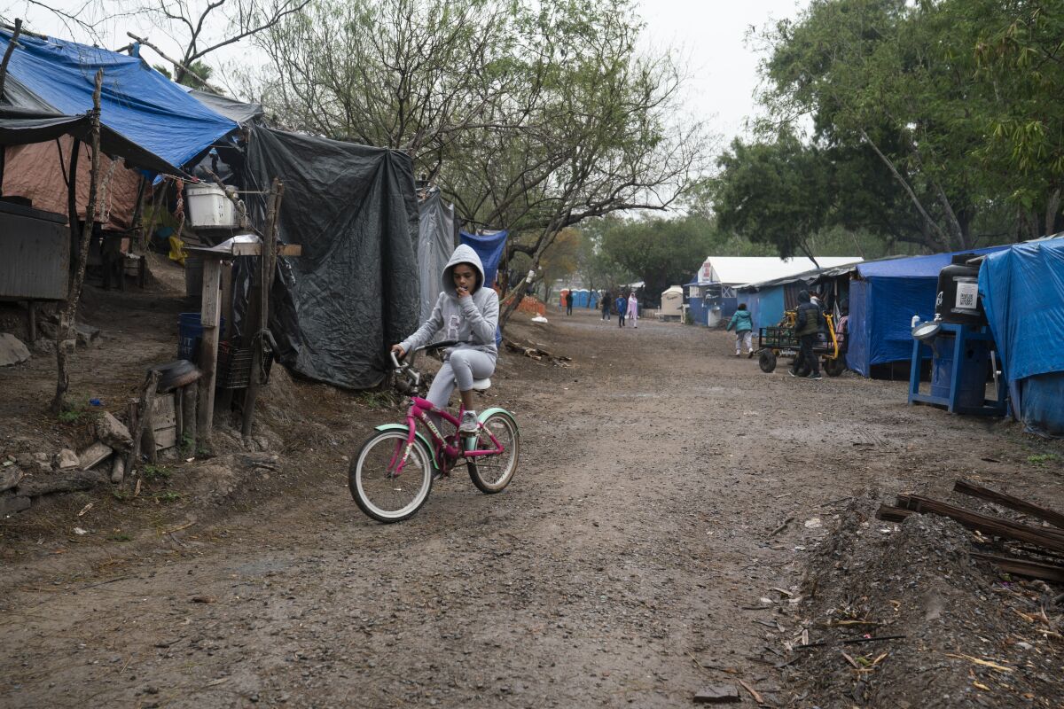 A girl rides her bike in a migrant camp 