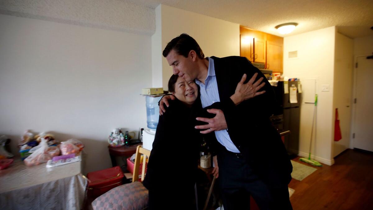 Zenaida Jose, 67, left, hugs Jordan Pynes, the president of Thomas Safran & Associates, in her Wilshire Towers apartment.