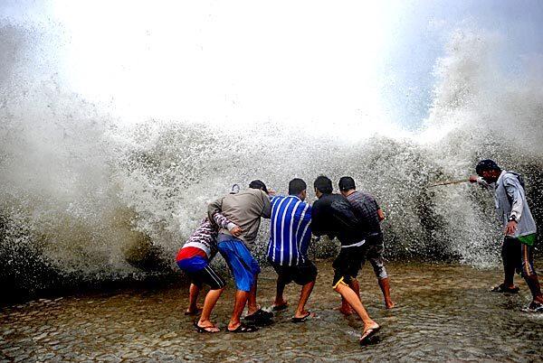 Waves from Typhoon Nesat inundate a seawall on Roxas Boulevard in Manila. At least seven people were killed as Nesat lashed the Philippines, authorities said, bringing waist-deep floods, blackouts and dramatic storm surges.