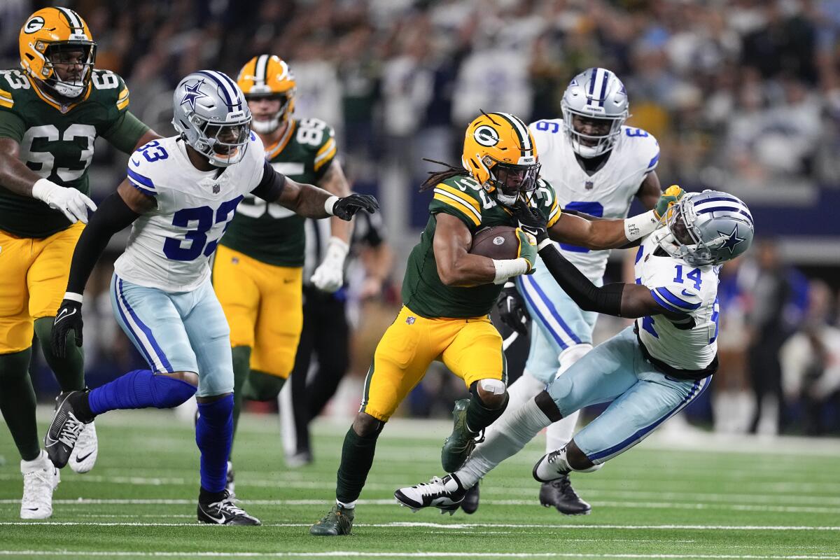 Packers running back Aaron Jones (33) applies a stiff-arm on Dallas Cowboys safety Markquese Bell (14).