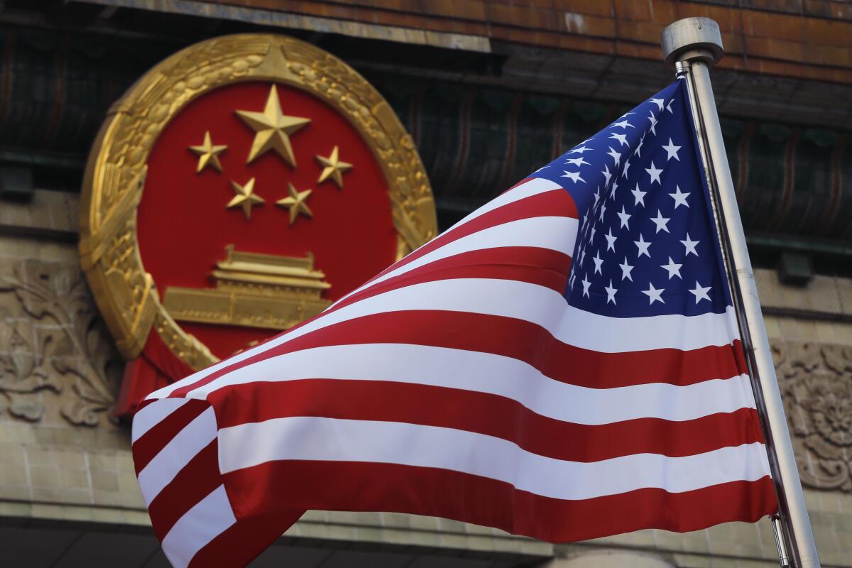 Una bandera estadounidense junto al emblema nacional de China.