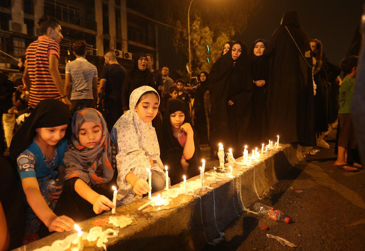 Varias personas encienden velas en el lugar de un atentado masivo en Karada, un concurrido distrito comercial donde muchas de las víctimas realizaban compras para el feriado del Eid al-Fitr, en el centro de Bagdad, Irak, el 4 de julio de 2016. (AP Foto/Hadi Mizban)