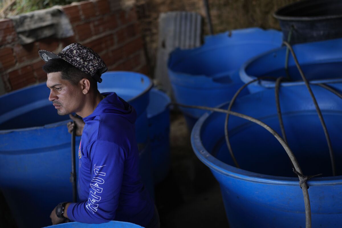 A man sits among several large blue water tanks