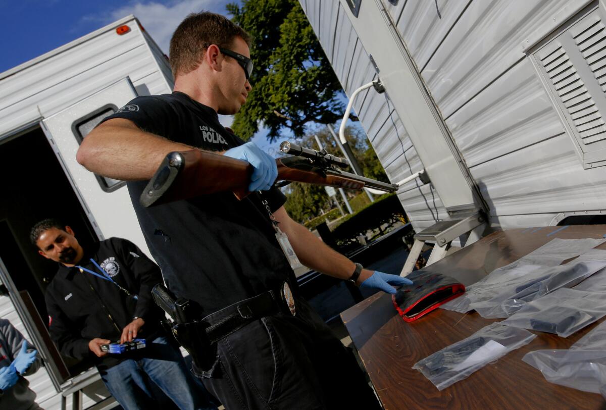 An officer unpacks a gun at a news conference where authorities announced the arrests of 19 alleged MS-13 members or associates.