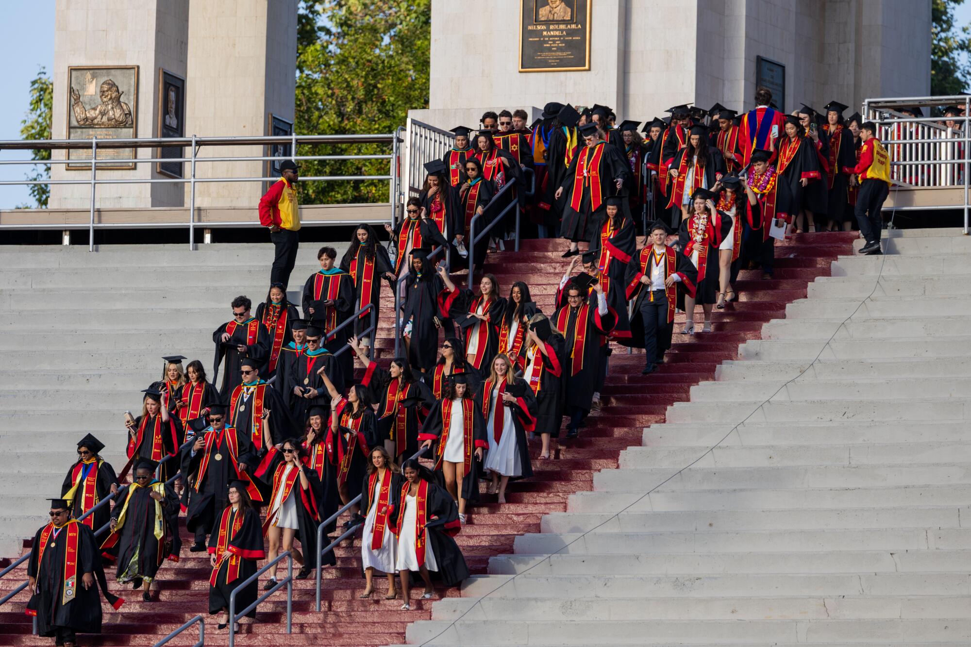 USC graduates walk down stairs at Los Angeles Memorial Coliseum.