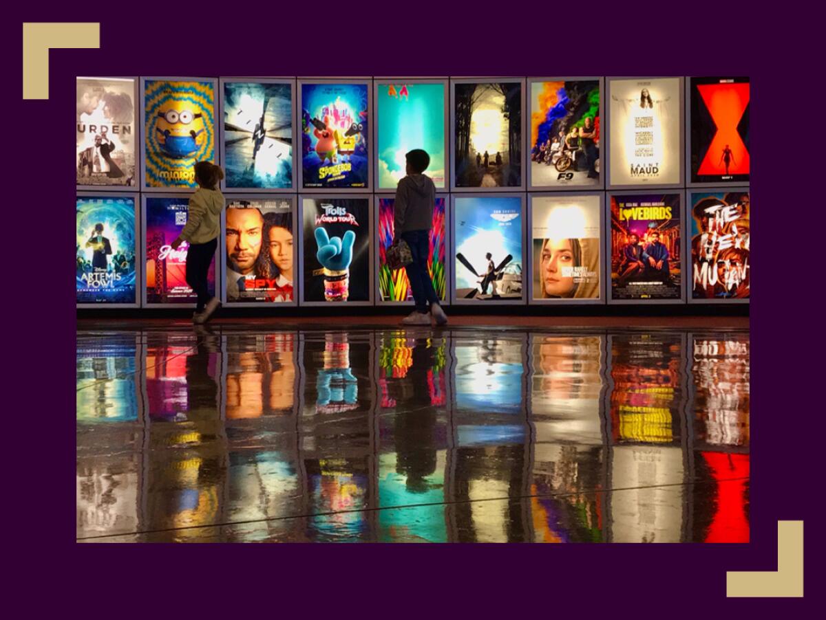 Two children looks at movie posters inside the lobby of the Arclight movie theater In Manhattan Beach, Ca.