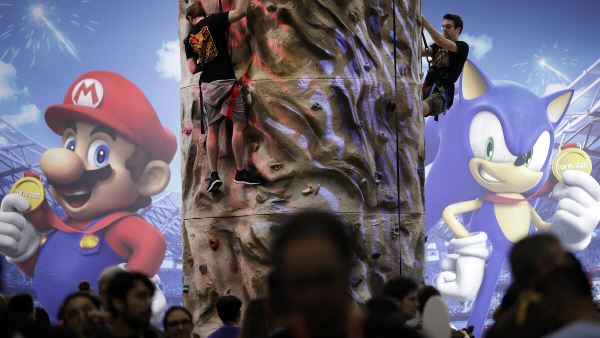 Guests climb a wall at Nintendo’s “Mario and Sonic at the Olympic Games” display during E3.