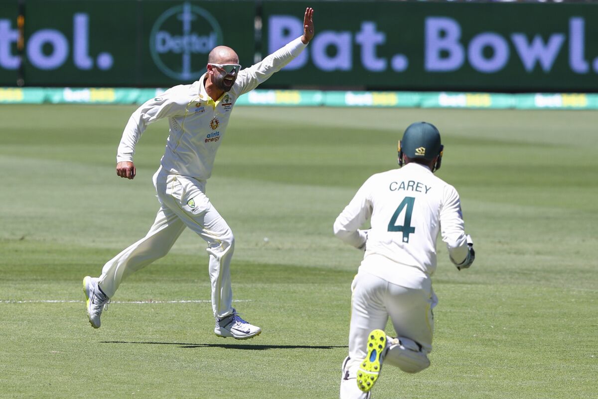 Australia's Nathan Lyon, left, celebrates after taking the wicket of England's Ollie Pope during day four of the first Ashes cricket test at the Gabba in Brisbane, Australia, Saturday, Dec. 11, 2021. (AP Photo/Tertius Pickard)
