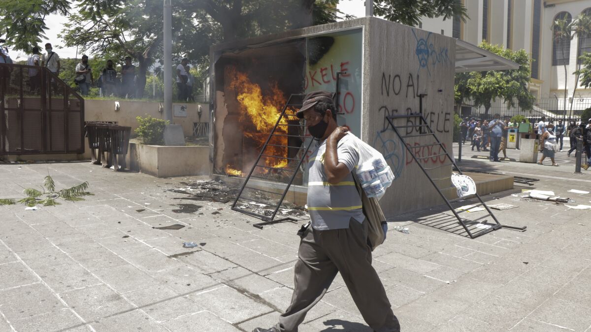 A Chivo digital wallet ATM, which exchanges cash for Bitcoin cryptocurrency, burns after being torched during a protest against President Nayib Bukele in San Salvador, El Salvador, Wednesday, Sept. 15, 2021. Thousands marched against the government of President Bukele, centered on fears Bukele may try for re-election in 2024. (AP Photo/Ivan Manzano)
