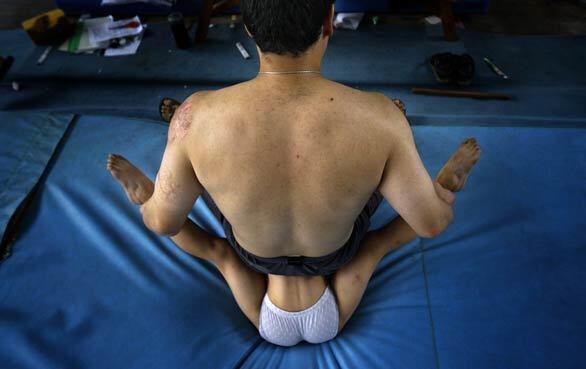A coach helps a young gymnast with flexibility exercises at a sports training center in Beijing. The training centers, of which there are hundreds across the country, help identify talented children who can be selected for sports schools where they receive an education and sports training aimed at turning them into world-class athletes.