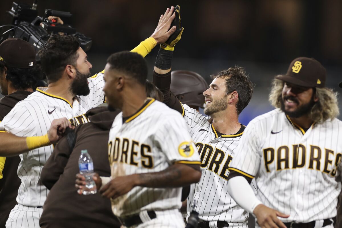 The Padres' Austin Nola, second from right, is congratulated by Eric Hosmer, left, after driving in the winning run.