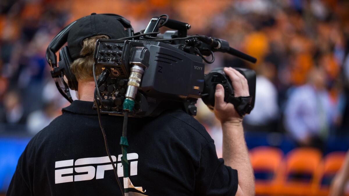 A cameraman working for ESPN network operates a camera at court side.