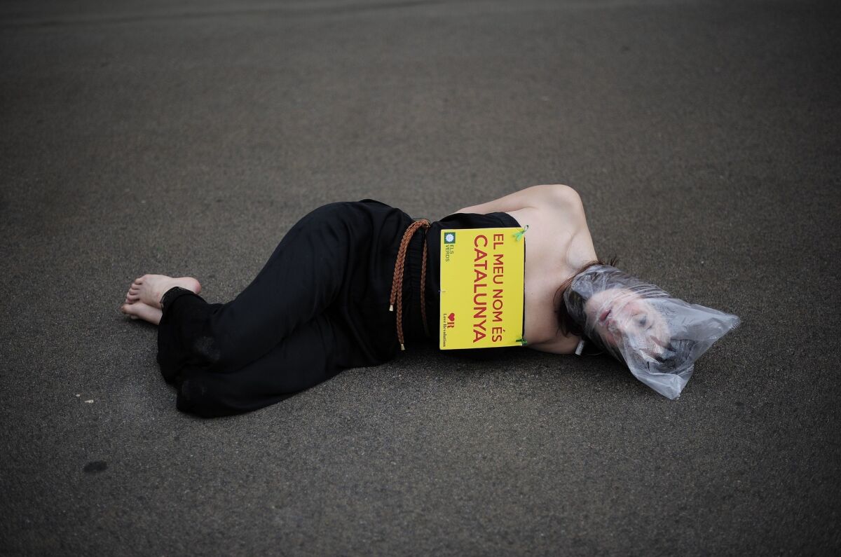 An pro-independence protester with a plastic bag on her head and a banner reading "My name is Catalonia" lies on the ground outside Catalonia's parliament in Barcelona during a vote on a petition to the national parliament to allow a referendum on independence.