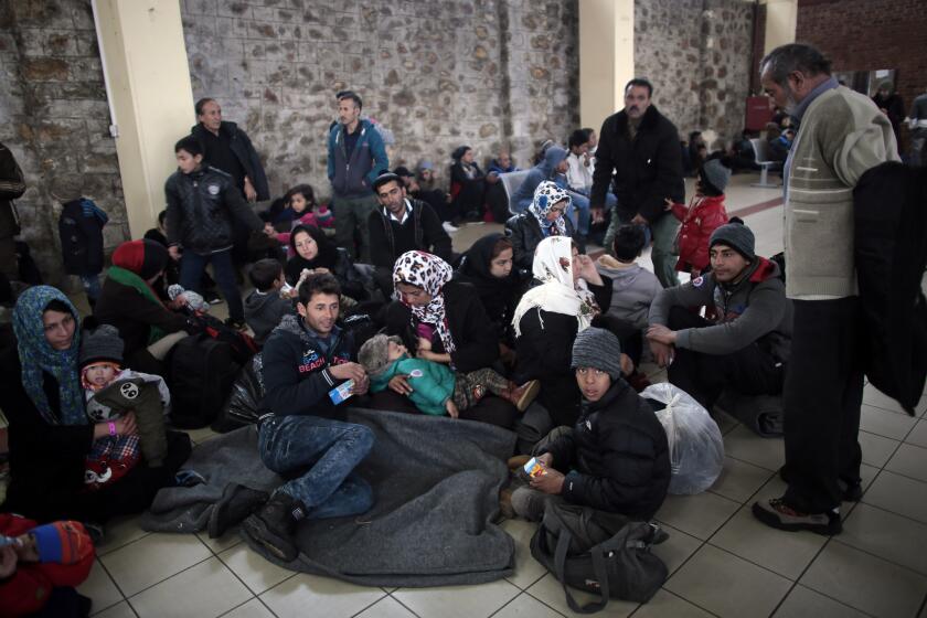 Migrant families wait in a terminal building after arriving from the Aegean Islands into the port of Piraeus, where many Afghan migrants have become stranded in Athens.