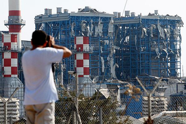 A man takes pictures of the power plant in Zygi, Cyprus, that was wrecked by an explosion of munitions at a nearby military base.