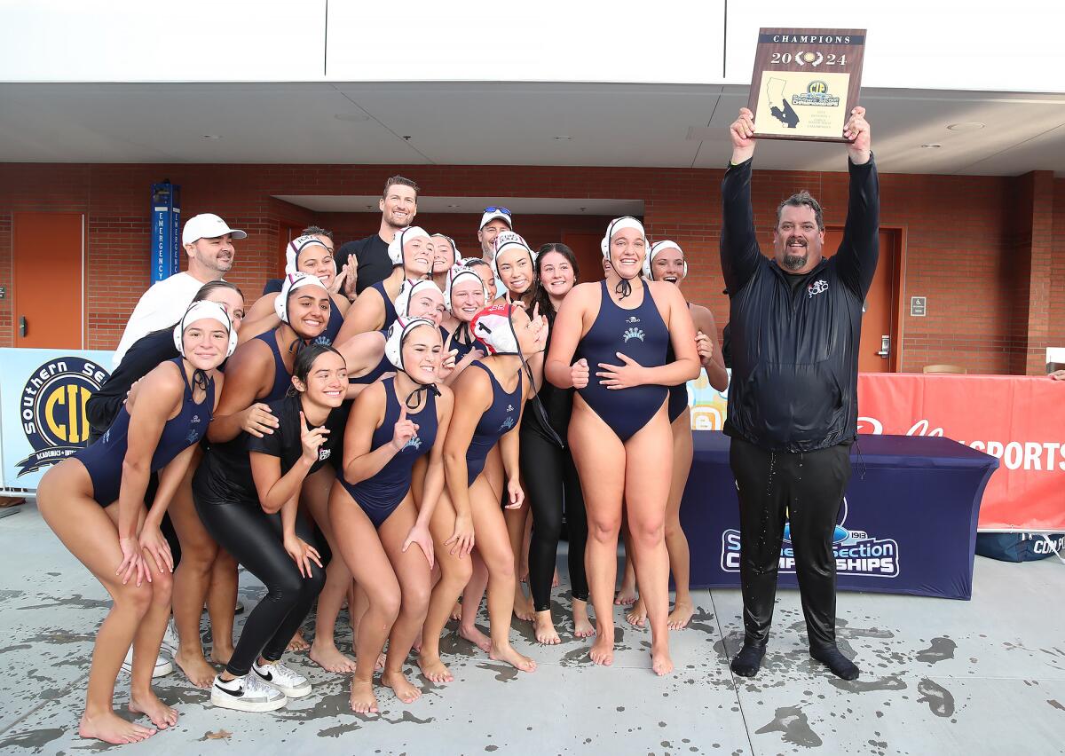 Marc Hunt holds the CIF trophy with the Corona del Mar girls' water polo team on Saturday.