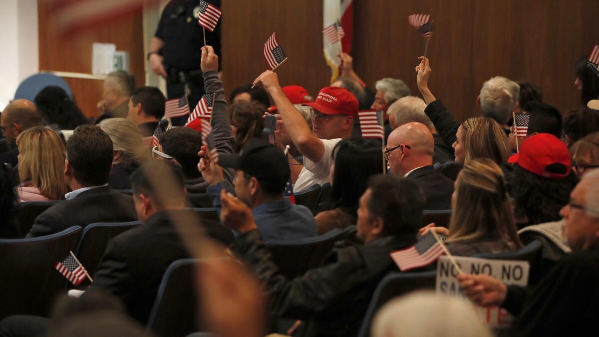 Opponents of Senate Bill 54 cheer and wave U.S. flags during a Costa Mesa City Council meeting May 1. The Costa Mesa City Council discussed whether to take an official stand against Senate Bill 54, California’s “sanctuary state” law.