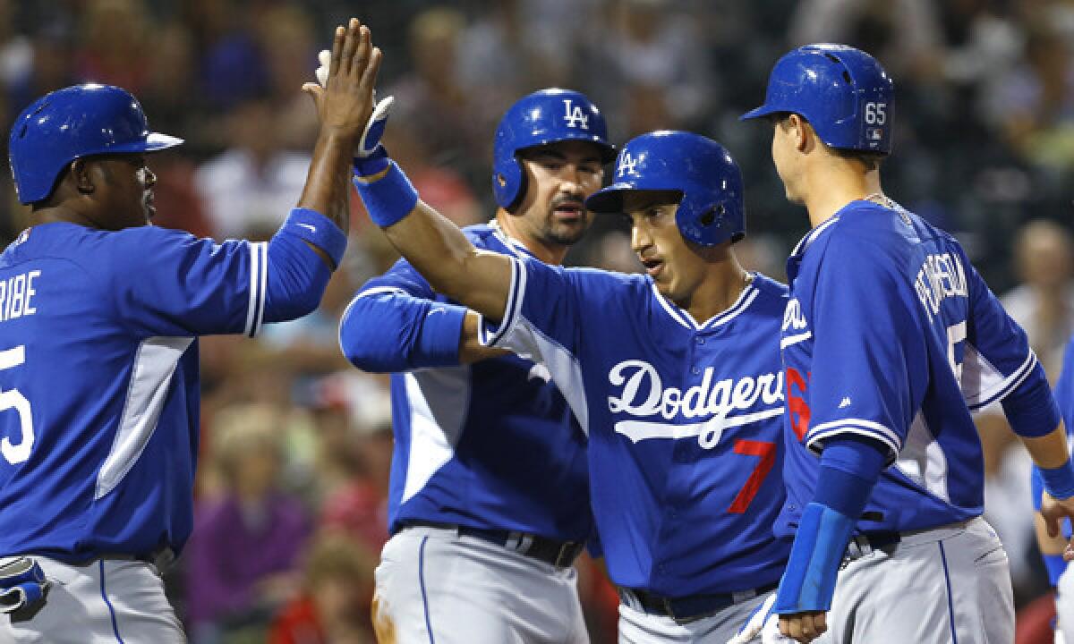 Dodgers infielder Alex Guerrero, second right, is congratulated by teammates Juan Uribe, left, and Adrian Gonzalez, second left, after hitting a fifth-inning grand slam in a Cactus League game against the Cincinnati Reds on Wednesday.