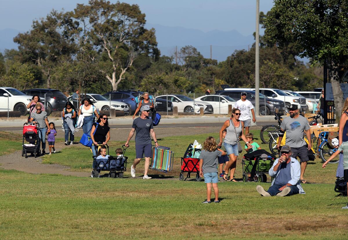 Families with children in hand walk into Fairview Park for the Concert in the Park at Fairview Park in Costa Mesa on Tuesday.