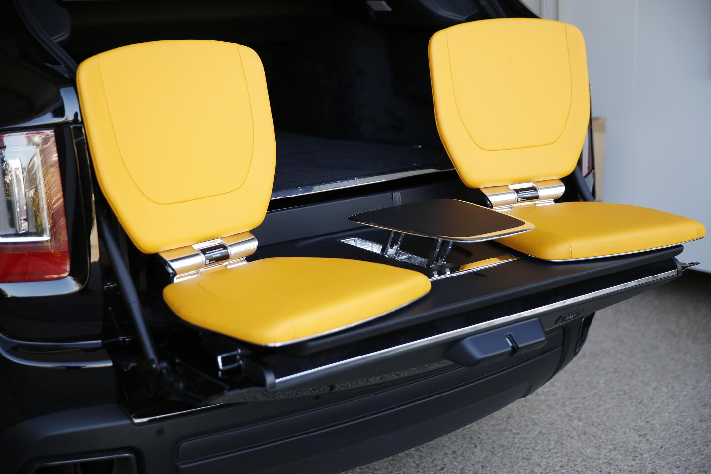 Two yellow "tailgating" seats at the back of a Rolls-Royce Cullinan Black Badge.