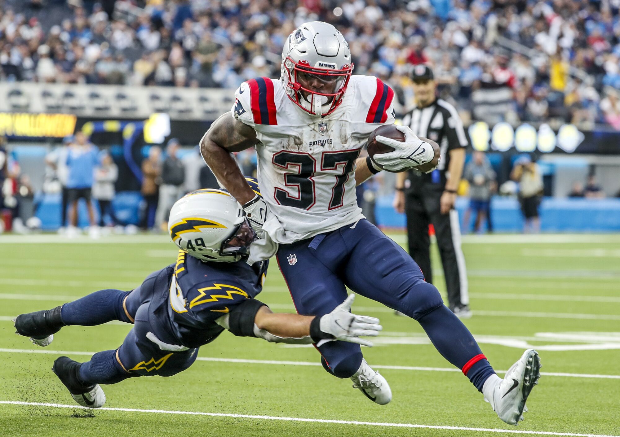 New England Patriots running back Damien Harris is tackled by Chargers linebacker Drue Tranquill.