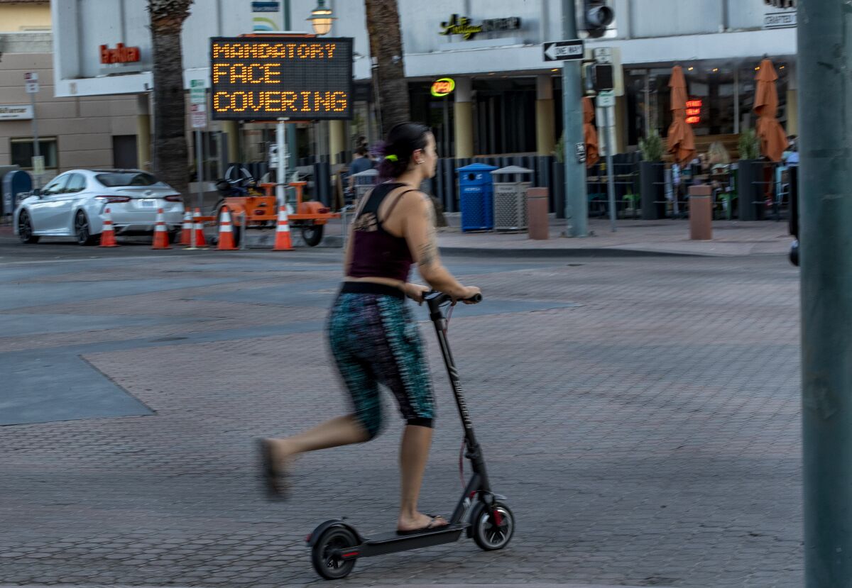 A woman on a scooter ignores the mandatory mask order in downtown Palm Springs in Riverside County.