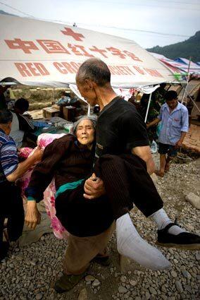 Earthquake survivor Yang Lingan, 82, is carried by her husband to a medical tent for treatment at a Chinese Red Cross refugee camp in Mianyang, China.