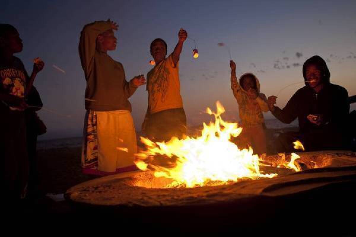 Members of the Sasser–Williams family of Los Angeles roast marshmallows at a fire pit at Dockweiler State Beach. Citing health concerns, air quality officials have proposed a year-round ban on open burning on all L.A. and Orange County beaches.