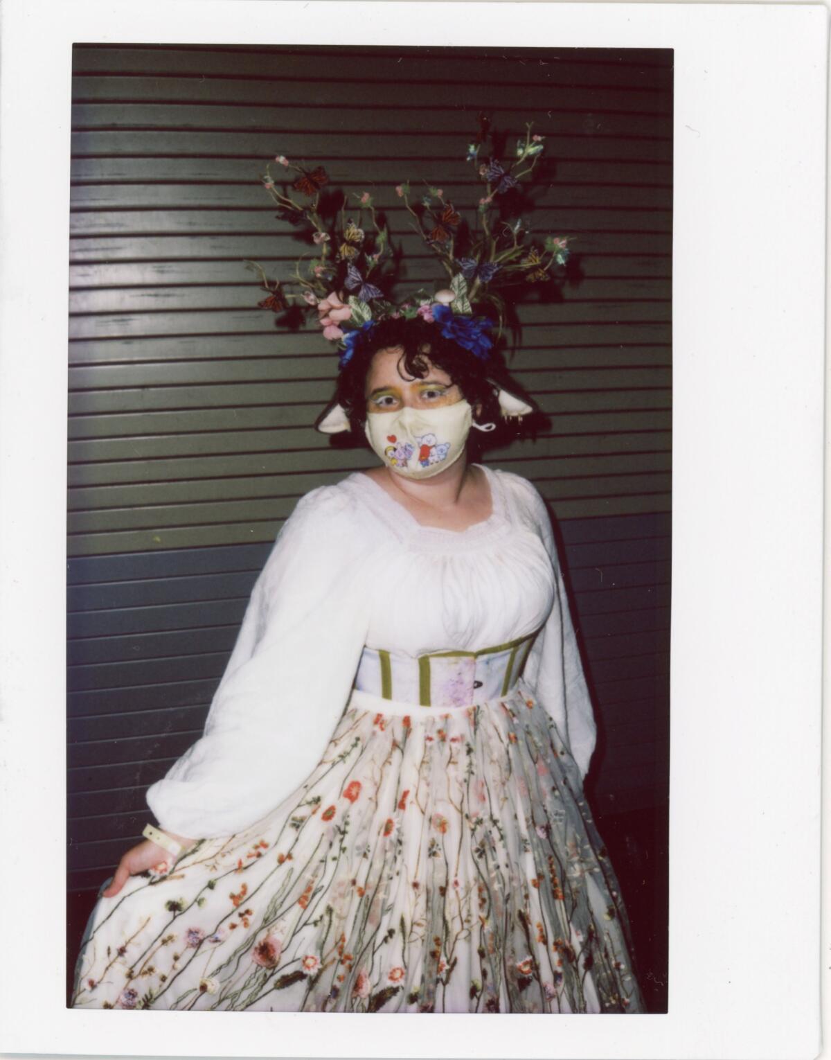 A woman in a white blouse and patterned skirt wears a black headdress.