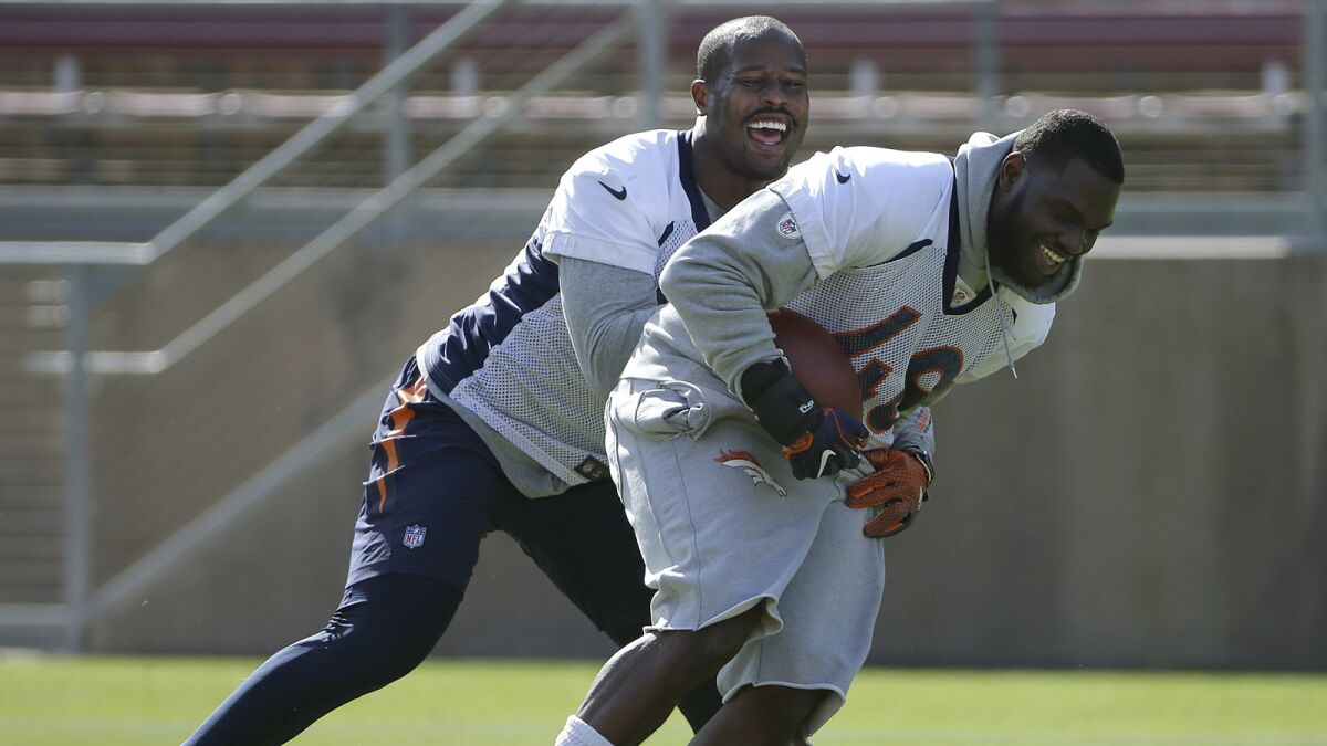 Denver Broncos linebacker Von Miller, left, laughs as he grabs linebacker Shaquil Barrett during a drill at an NFL football practice/