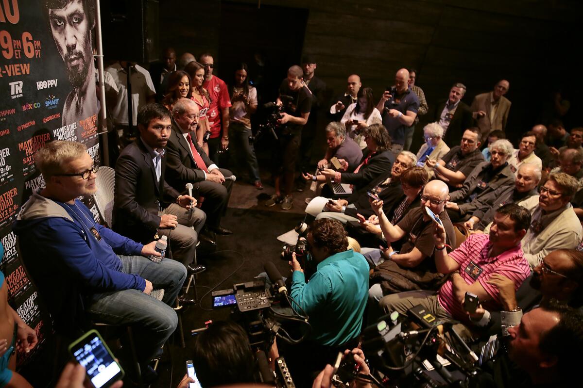 Manny Pacquiao, center, joins trainer Freddie Roach, left, and promoter Bob Arum, right, in an interview with print journalists backstage at the KA Theater at the MGM Grand Hotel.