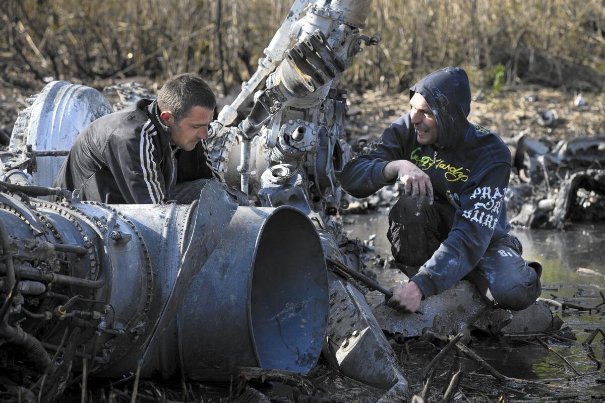 Residents gather parts of downed Ukrainian military helicopter near the town of Raigorodok, outside Slovyansk. The copter made an emergency landing and was later destroyed to ensure that it did not fall into the wrong hands.
