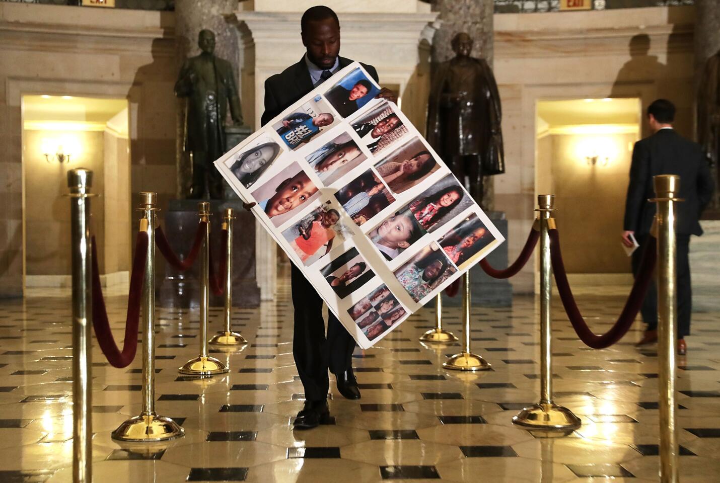Charles Bolden, staff assistant of Rep. Robin Kelly (D-Ill.), holds a poster with pictures of gun violence victims from Chicago as he walks towards the House Chamber on June 22, 2016.