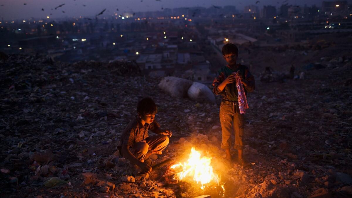 Indian workers warm themselves near a fire after sorting through garbage and picking out recyclable materials to sell from the Ghazipur landfill in east Delhi, India, in 2010.