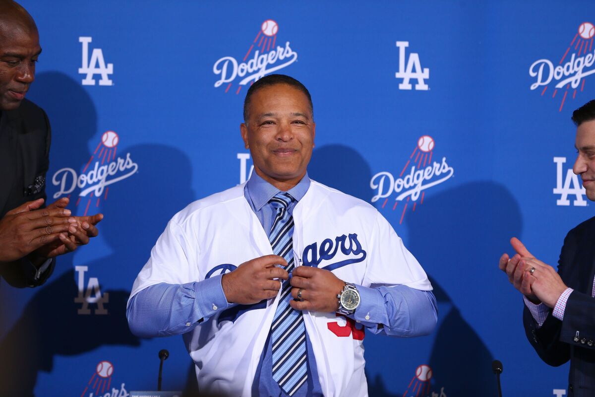New manager Dave Roberts puts on a Dodgers jersey at the news conference Tuesday.