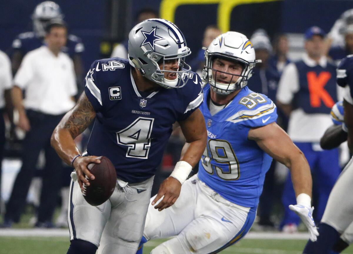 Chargers defensive end Joey Bosa (99) forces Cowboys quarterback Dak Prescott to scramble from the pocket during the fourth quarter Thursday.