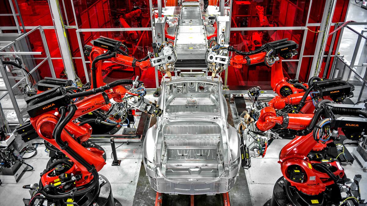 Robots assemble parts of a car at Tesla's factory in Fremont.