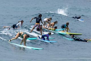 Laguna Beach, CA - August 10: A crowd of surfers attempt to ride a wave together as beach-goers frolic in the amid warm water on a hot and humid summer day in Laguna Beach Thursday, Aug. 10, 2023. (Allen J. Schaben / Los Angeles Times)
