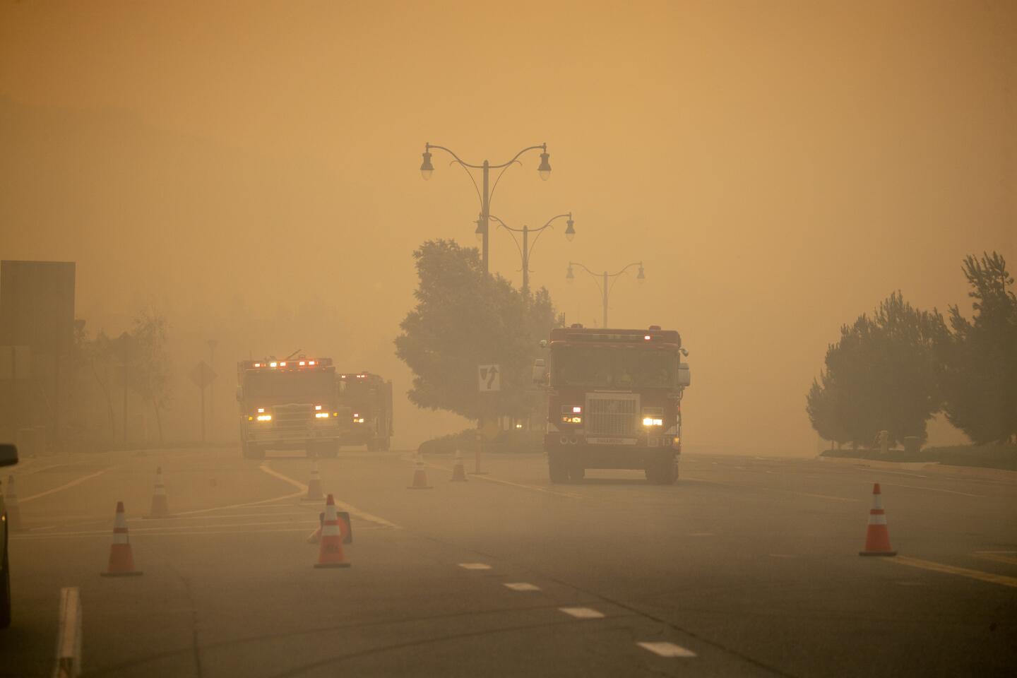 Firetrucks drive in a smoky haze