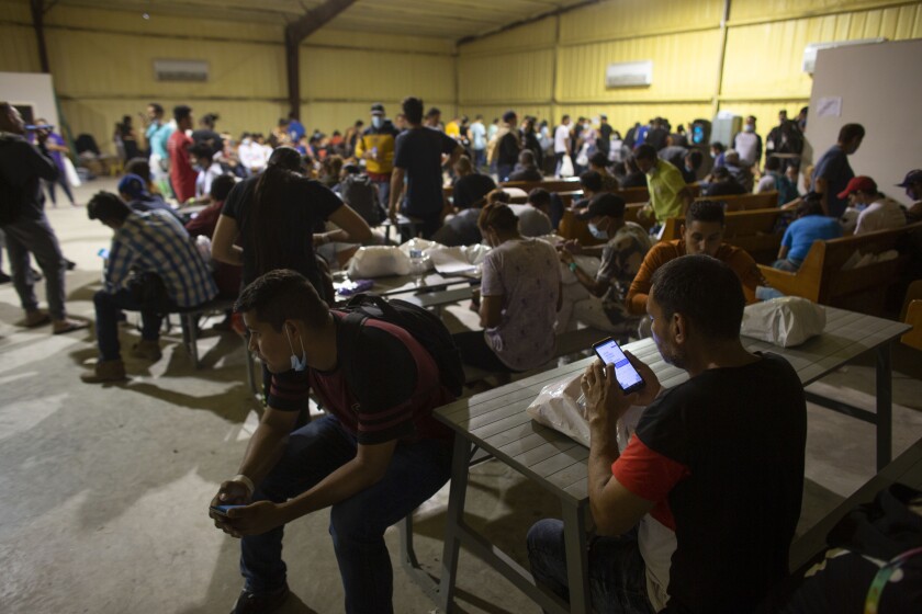 Decenas de personas esperan instrucciones en un centro de ayuda al migrante dirigido 