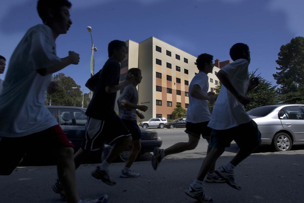 A group of athletes run past Mary Park Hall at San Francisco State University.