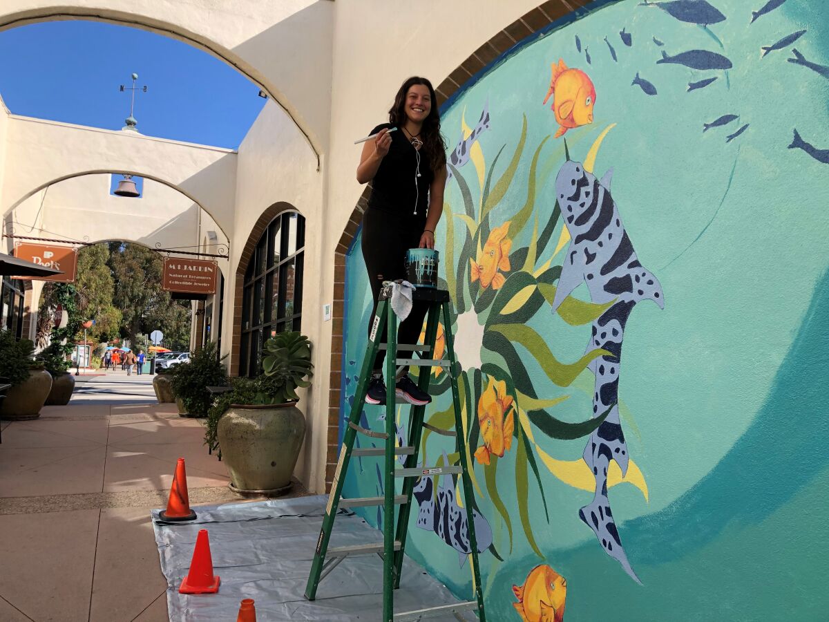 Melanie Atesalp works on her new sea-life mural on the Arcade Building on Wall Street in La Jolla.