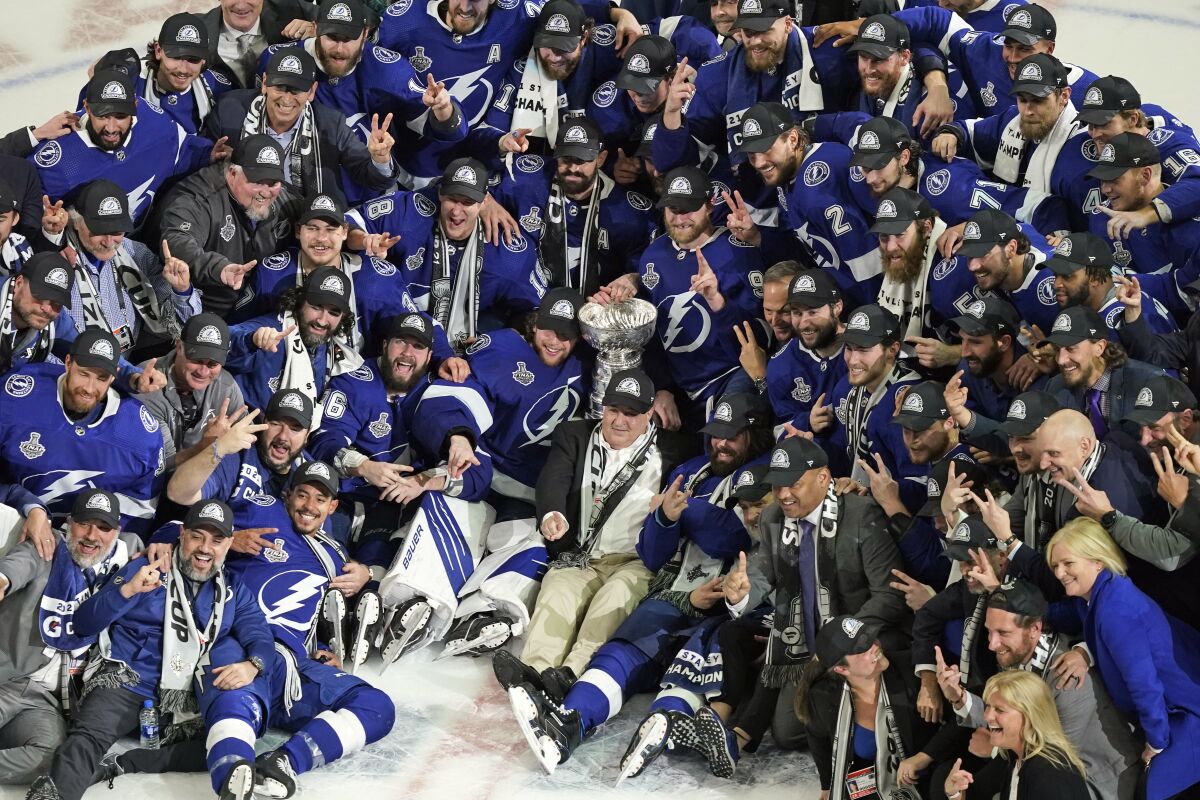 FILE - In this July 7, 2021, file photo, the Tampa Bay Lightning team poses with the Stanley Cup after Game 5 of the NHL hockey Stanley Cup finals against the Montreal Canadiens in Tampa, Fla. The Lightning won the Stanley Cup back-to-back not just because they were the best hockey team on the ice. They were also the NHL's best in the front office managing the salary cap made even more difficult because of pandemic revenue losses. (AP Photo/Gerry Broome, File)
