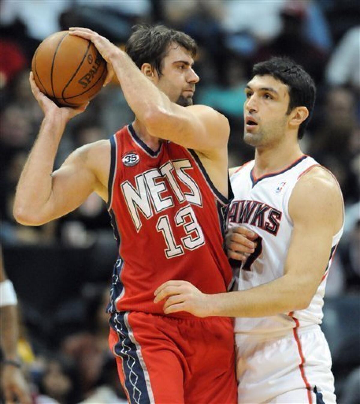 New Jersey Nets center Mehmet Okur, left, of Turkey, keeps the ball away from Atlanta Hawks center Zaza Pachulia, of Georgia, in the first half during an NBA basketball game on Friday, Dec. 30, 2011, at Philips Arena in Atlanta. (AP Photo/Erik S. Lesser)