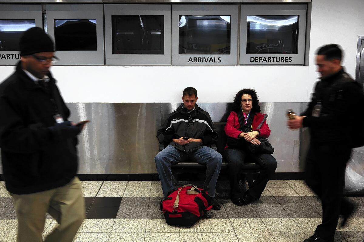At New York's LaGuardia Airport, two travelers wait in the ticketing area of Terminal B, where the "arrivals" and "departures" screens are showing no information.