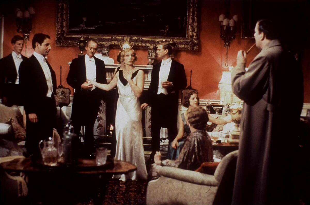 Men in tuxedos stand around a woman in an evening gown.